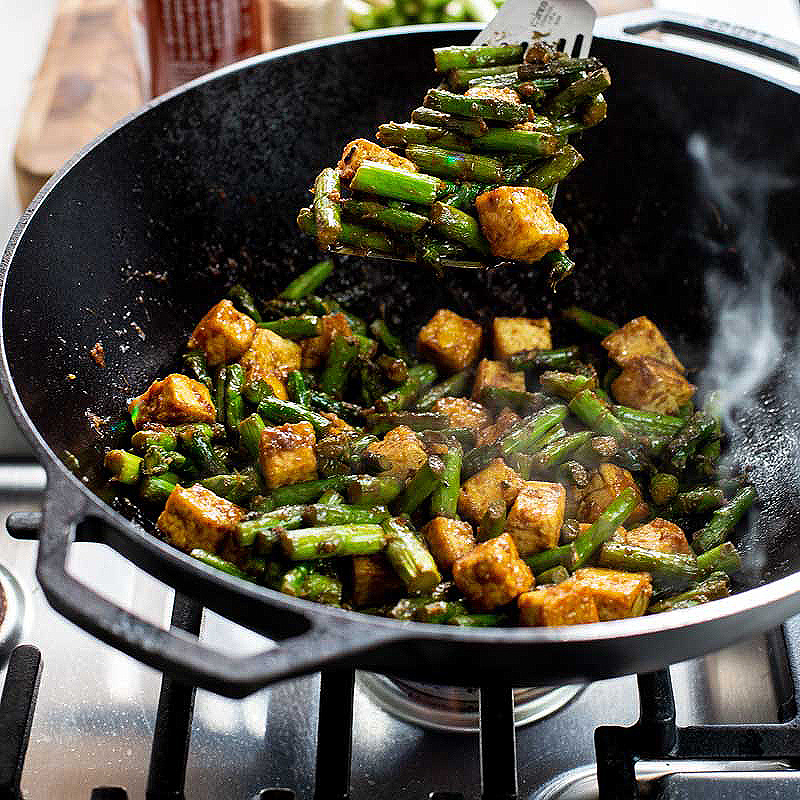 Lodge Pro Cast Iron Wok with chicken and asperagus cooking turned by a fish turner