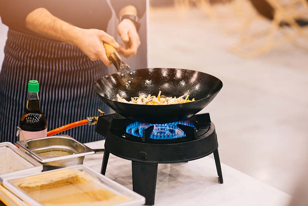 Chef cooking in a wok on a propane burner