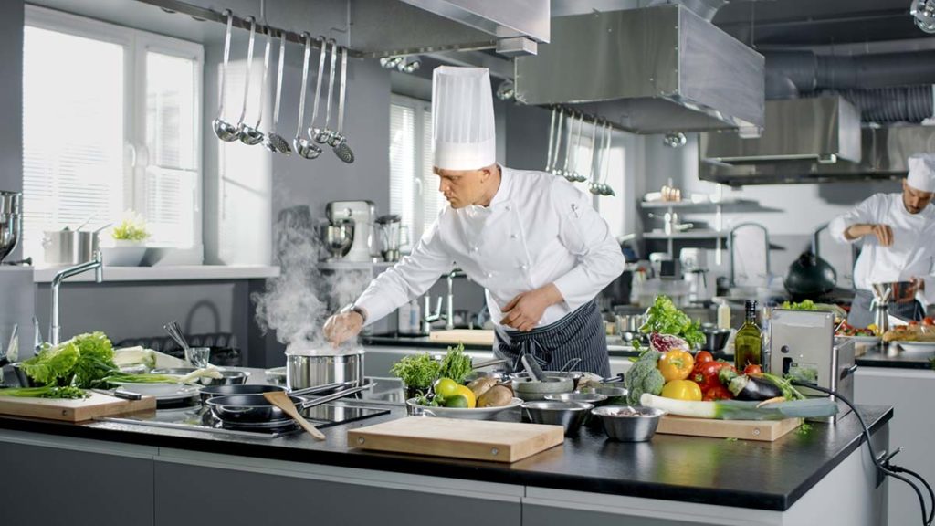 A professional chef cooking a sauce in a restaurant kitchen
