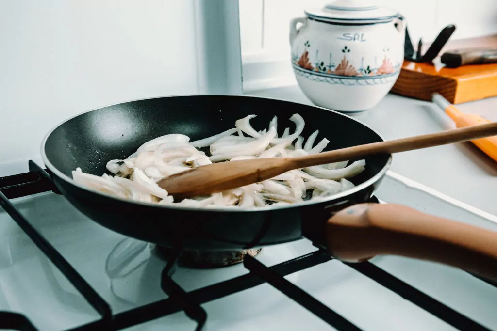 PTFE PFOA non-stick pan cooking onions stiring with wooden spoon